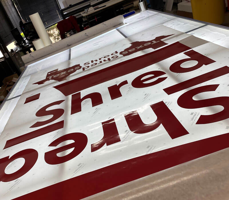 large vinyl sticker being weeded on a lightbox
